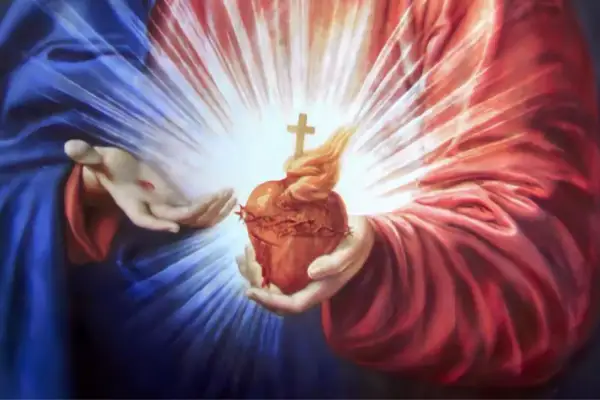 Dłonie trzymają gorejące Serce Jezusa, symbol miłości i drogi do rozwoju duchowego.